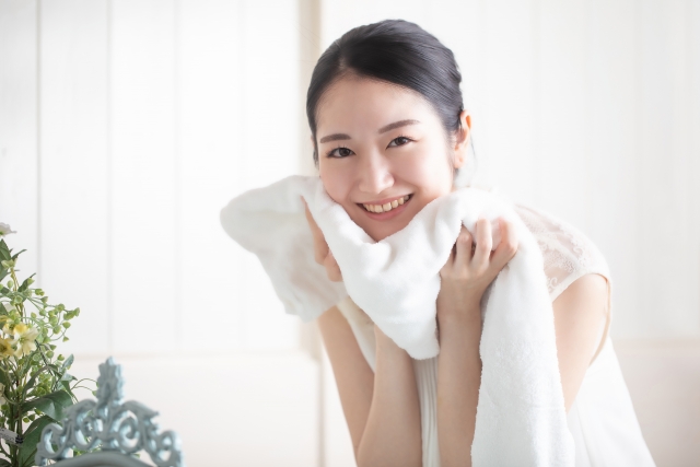 バスタオルで顔を拭いている若い女性