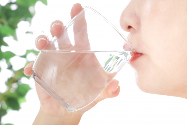 グラスのお水を飲む若い女性