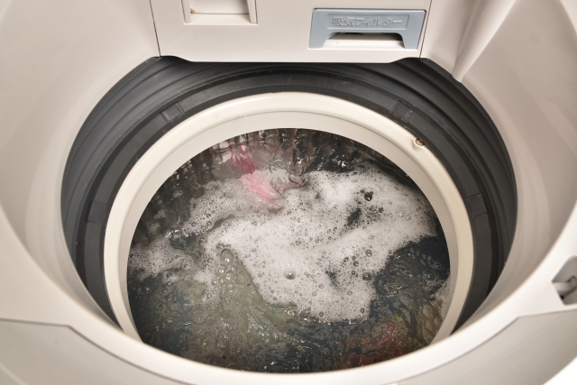 全自動動洗濯機で洗濯しているようす。蓋が開いていて泡立っている。