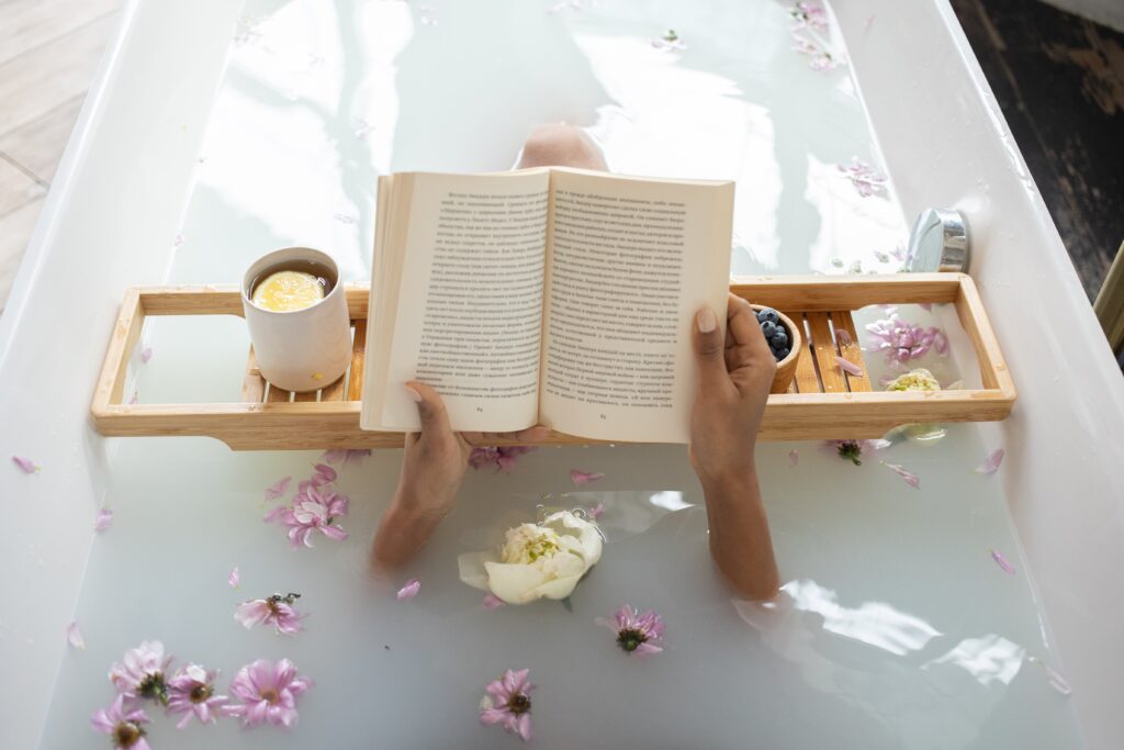 入浴剤を入れた湯船に浸かり本を読んでいる女性