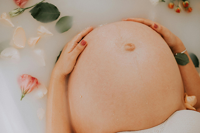 妊娠中の女性が湯船に浸かり、大きなおなかを見せている