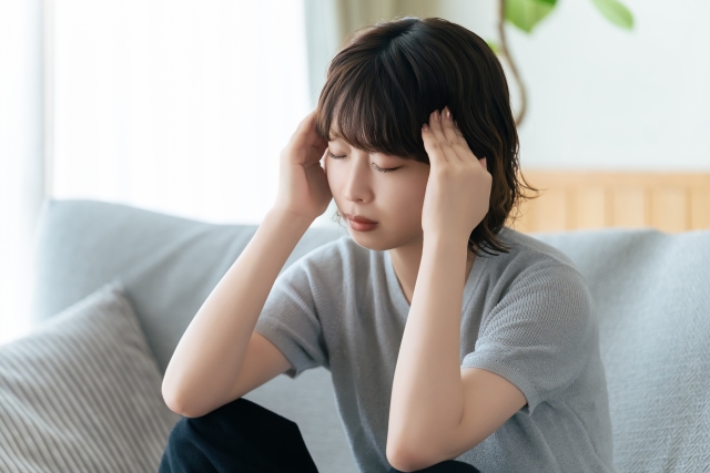 頭を押さえて悩む女性