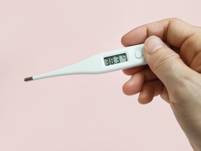 発熱し、体温を測る女性の手