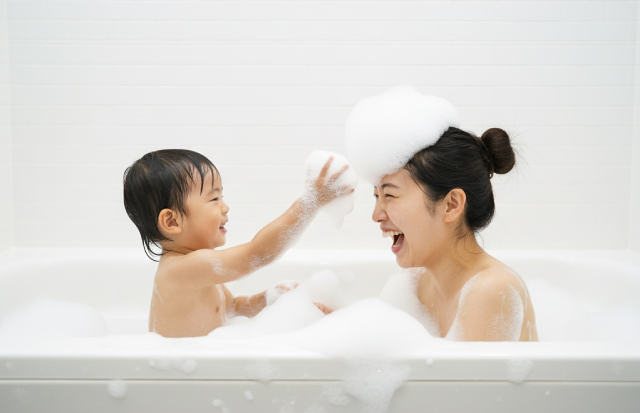 泡たっぷりのバスタブの中で楽しんでいる親子