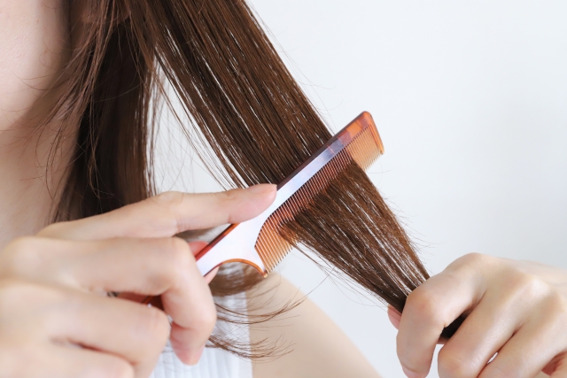 櫛で髪の毛をとかす女性