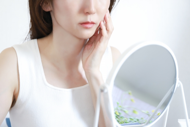 スキンケアをしながら鏡を見る女性