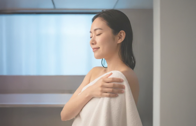 風呂上がりに肌をやさしく拭いている若い女性