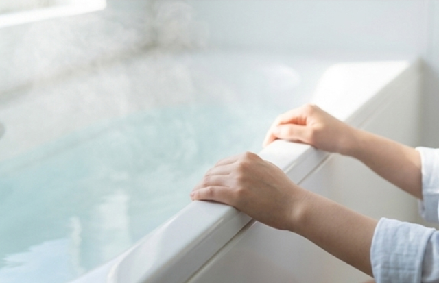 朝の明るく清潔な浴室で入浴の準備をしている若いアジア人女性