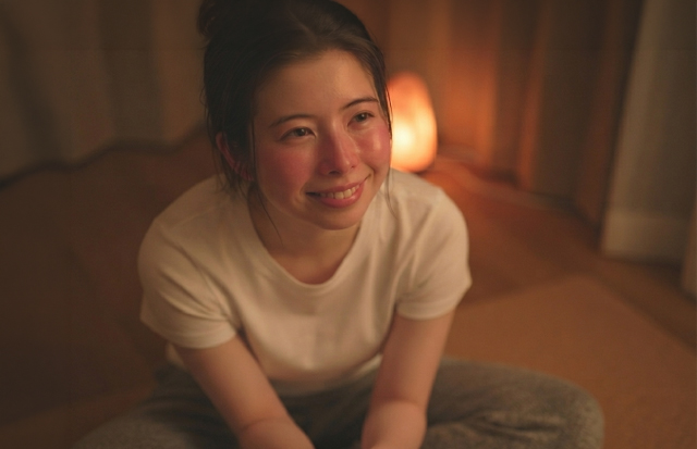 ヨガマットの上で軽く体をほぐしている若い女性