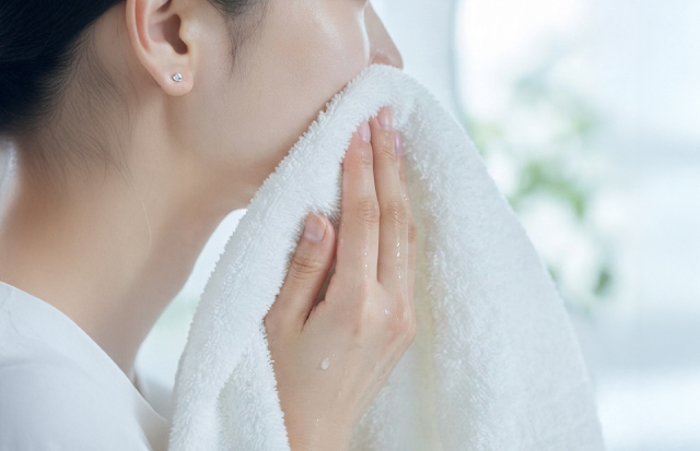 お風呂上りに鏡に向かい、毛穴をチェックしている女性