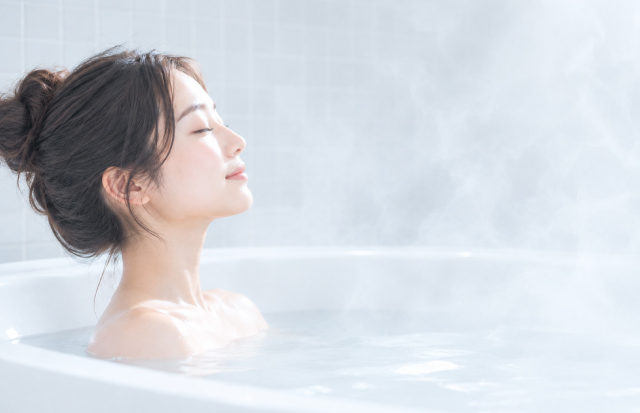 湯気に包まれバスタブに浸かる女性