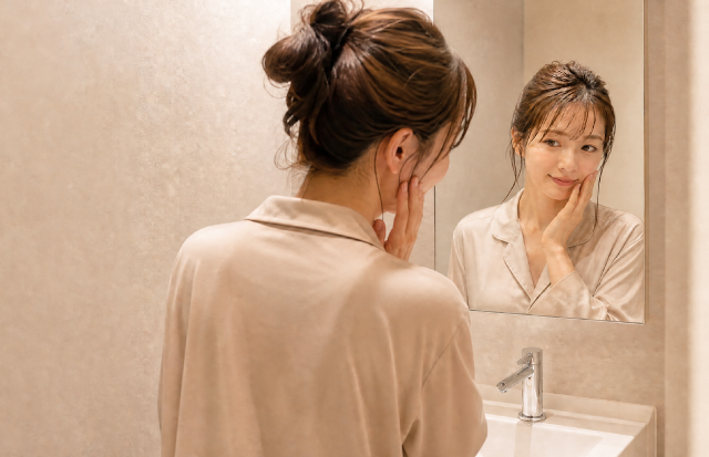 洗面所の鏡越しに、スキンケアをする女性